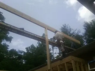 Carpenter setting a ridge beam over a new addition frame — Ice Dam Removal by Roofing Brothers in Polk City