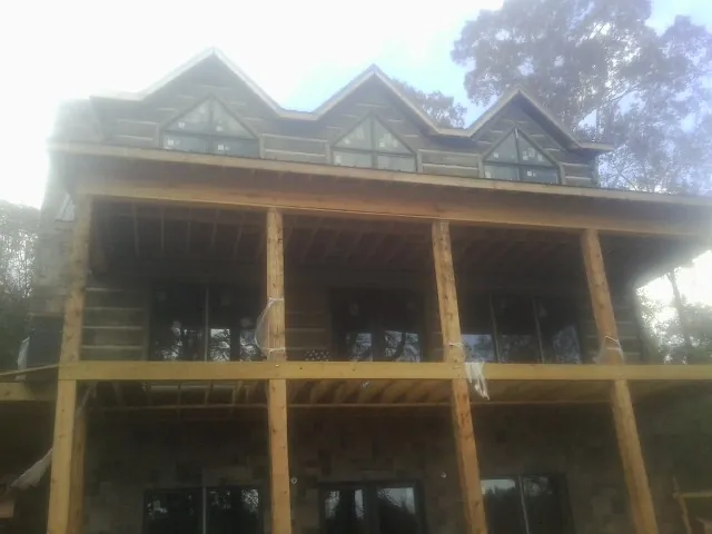 Dormers and porch framing on a large log home under construction — Roof Coating work by our crew in Polk City