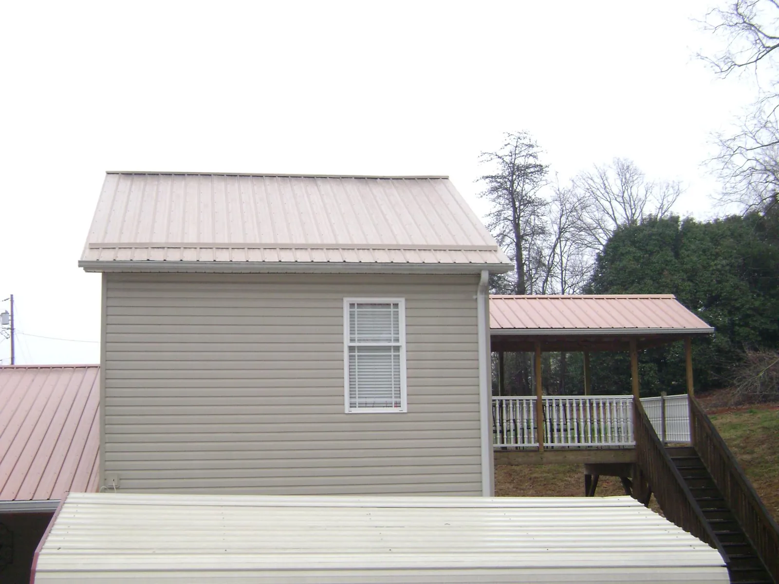 Tan metal roofs on a two story addition and attached porch, from a Roof Replacement job in Polk City